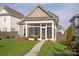 Back exterior of home with sunroom addition, green grass and landscaping at 13818 Jacks Ln, Pineville, NC 28134