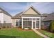 Back exterior of home with sunroom addition, green grass and landscaping at 13818 Jacks Ln, Pineville, NC 28134