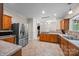 Open kitchen with stainless steel refrigerator, tile floors, granite counters, and wooden cabinets at 140 Ribbon Cir, Lincolnton, NC 28092