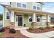 Charming two-story home featuring a covered porch with stone accents, green siding, and manicured landscaping at 16019 Kelby Cv, Charlotte, NC 28278