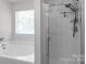 Bathroom featuring a tub with a window and shower with a glass enclosure and modern fixtures at 1800 Oriole Ct, Monroe, NC 28112