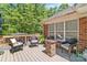 A backyard deck with outdoor seating and a brick fireplace, set against a lush green backdrop at 1800 Oriole Ct, Monroe, NC 28112