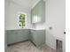 Laundry room with washer hookups, upper and lower sage green shaker style cabinetry, and a window at 1829 Union St, Charlotte, NC 28205