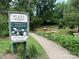 Sign for Plaza Midwood Community Garden, growing together since 2004, with a pathway leading into the garden at 2015 Club Rd, Charlotte, NC 28205