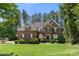 Charming two-story brick home featuring a well-manicured lawn, mature trees, and classic architectural details at 221 Silvercliff Dr, Mount Holly, NC 28120