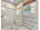 Modern shower area with white subway tile, glass enclosure, and window, set against decorative wallpaper at 2501 Richardson Dr, Charlotte, NC 28211