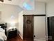 Vaulted ceiling with skylight highlight this bedroom, featuring a wooden barn door and black bedside table at 2600 Kirkholm Dr, Matthews, NC 28105