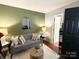 Inviting living room with a green accent wall, cozy gray sofa, and a stylish round wicker table at 2600 Kirkholm Dr, Matthews, NC 28105