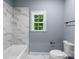 Bathroom with marble tiled walls, new toilet, and a window letting in plenty of natural light at 2694 Woodcrest Sw Dr, Concord, NC 28027