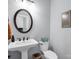 A well-lit bathroom with a pedestal sink and round mirror at 270 Conifer Way, Shelby, NC 28150