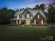 Charming two-story home with a brick and gray siding, a welcoming front porch, and landscaped yard at dusk at 270 Conifer Way, Shelby, NC 28150