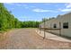 Gravel driveway leading to a metal building with a concrete patio and lush green trees and field at 270 Worthington Dr, Mt Ulla, NC 28125