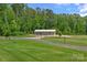 Exterior view of the rear of the home, showing lush green lawns and a metal stable with a white roof at 270 Worthington Dr, Mt Ulla, NC 28125