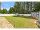 Spacious fenced backyard with lush green grass, mature trees, storage sheds, and a charming swing set at 311 Masters Dr, Rock Hill, SC 29732