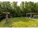 Sprawling backyard featuring lush greenery, a wooden pergola, and charming outdoor seating, ideal for relaxation and entertainment at 3186 Helmsley Ct, Concord, NC 28027