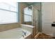 Tiled tub and shower area featuring glass doors and natural light at 3186 Helmsley Ct, Concord, NC 28027