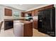 Well-lit kitchen featuring an island, black appliances, and dark cabinets at 3512 Gibbon Terrace Ct, Charlotte, NC 28269