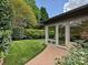 A well manicured backyard features artificial turf, landscaping, and a brick patio with glass enclosed sitting room at 5603 Ballinard Ln, Charlotte, NC 28277