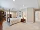 Bright bedroom features neutral walls, plush carpet, a four-poster bed, and an organized walk-in closet at 5603 Ballinard Ln, Charlotte, NC 28277