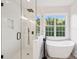 Luxurious bathroom with a glass-enclosed shower, freestanding tub, and a large window with natural light at 5745 Snapdragon Ln, Huntersville, NC 28078