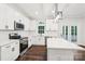 A modern kitchen features stainless steel appliances, white cabinetry, and a center island with quartz countertop at 5745 Snapdragon Ln, Huntersville, NC 28078