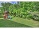 Spacious backyard featuring a wooden playset, green lawn, and mature trees, ideal for Gathering fun at 6618 Vizcaya Ct, Charlotte, NC 28226
