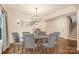Formal dining room with modern chandelier, hardwood floors, and six upholstered chairs at 6618 Vizcaya Ct, Charlotte, NC 28226