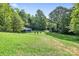 Large backyard featuring lush green grass, fire pit, and seating, surrounded by mature trees at 715 Potneck Rd, Salisbury, NC 28147