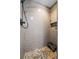 Modern walk-in shower with stylish tile work, pebble flooring, and convenient shelving for toiletries at 715 Potneck Rd, Salisbury, NC 28147