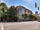 Multi-story condo building with brick facade, large windows, and balconies surrounded by green trees at 718 W Trade St # 704, Charlotte, NC 28202