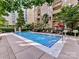Community pool surrounded by lush landscaping, lounge chairs, and umbrellas at 718 W Trade St # 704, Charlotte, NC 28202