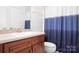 Bathroom with a wood vanity, mirror, toilet and blue and white shower curtain at 7525 Blackgum Falls Ct, Huntersville, NC 28078