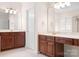 A bathroom with wood cabinets, a white door, two mirrors, and decorative lights above the vanity at 7525 Blackgum Falls Ct, Huntersville, NC 28078