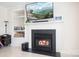 Living room fireplace with a solid mantle, large screen television and built-in shelving at 7525 Blackgum Falls Ct, Huntersville, NC 28078
