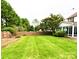 Expansive backyard featuring lush green lawn, privacy fence, mature trees, and sunroom at 8218 Lynnewood Glen Dr, Charlotte, NC 28269