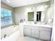 Well-lit bathroom featuring a dual sink vanity, framed mirrors, and a soaking tub at 8218 Lynnewood Glen Dr, Charlotte, NC 28269