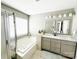 Bathroom with double sink vanity, shower, and soaking tub beneath a bright window at 8218 Lynnewood Glen Dr, Charlotte, NC 28269
