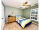 A simple bedroom with carpet flooring includes a ceiling fan, dresser, and large window at 8218 Lynnewood Glen Dr, Charlotte, NC 28269