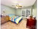A simple bedroom with carpet flooring includes a ceiling fan, dresser, and large window at 8218 Lynnewood Glen Dr, Charlotte, NC 28269