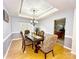 Lovely dining room with hardwood floors, tray ceiling, and a view to the kitchen; table is set for dinner at 8218 Lynnewood Glen Dr, Charlotte, NC 28269