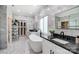 Modern bathroom features marble walls, standalone tub, dual vanities, and a glass shelving unit at 8707 Fairview Rd, Charlotte, NC 28226