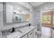 Bright bathroom featuring marble wall, dual sinks, granite countertop, and sleek black fixtures at 8707 Fairview Rd, Charlotte, NC 28226