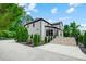 Side view of the white brick home featuring a patio, stairs, lush landscaping, and a driveway at 8707 Fairview Rd, Charlotte, NC 28226