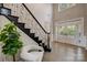 Sunlit foyer with hardwood flooring, a staircase with decorative iron spindles and bright white doors at 8707 Fairview Rd, Charlotte, NC 28226
