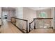 Hallway featuring decorative railing, modern chandelier, and hardwood floors at 8707 Fairview Rd, Charlotte, NC 28226