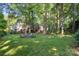 The backyard has a fire pit with chairs on a spacious, well-manicured lawn surrounded by lush trees at 9002 Maple Hill Ct, Huntersville, NC 28078