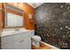 Stylish powder room boasting a vanity, mirror, and vibrant floral wallpaper at 9002 Maple Hill Ct, Huntersville, NC 28078