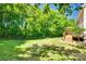 Spacious backyard featuring a lush lawn, mature trees, and a charming deck with seating at 9700 Stewart Spring Ln, Charlotte, NC 28216