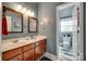 Well-lit bathroom featuring dual sinks with wood cabinets, and a separate toilet room at 9700 Stewart Spring Ln, Charlotte, NC 28216