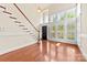 Bright living room featuring hardwood floors, a staircase, plantation shutters, and a front door at 1161 Stuarts Landing Dr, Cramerton, NC 28032